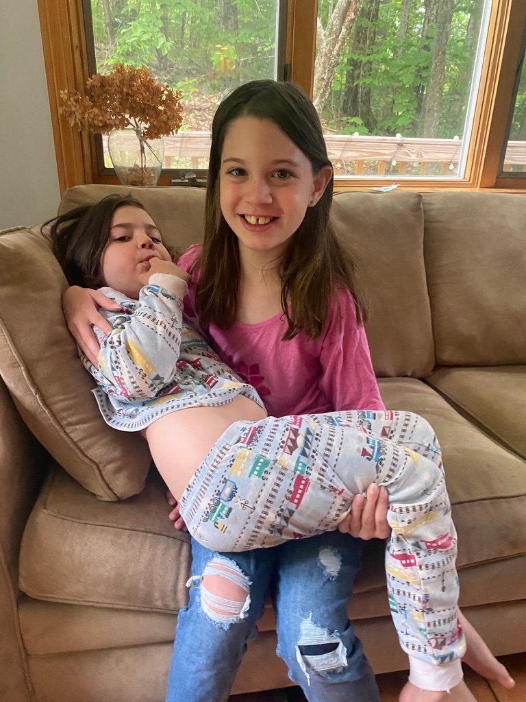 Iona sitting on a sofa with her younger sister on her lap
