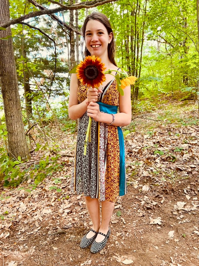 Iona standing on a woodland path holding sunflowers